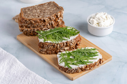 Sandwiches with curd cheese and arugula. Rye bread with seeds