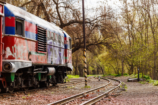 Abandoned railway vehicle on tracks with artistic graffiti amidst nature, vintage train carriage