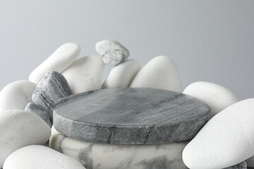 Presentation for product. Stone podium and pebbles on light grey background, closeup