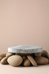 Presentation for product. Stone podium and pebbles on beige background. Space for text