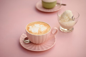 Appetizing cappuccino in a pink cup on a pink table close-up. Next to it are vanilla ice cream and matcha latte.