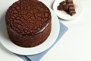 Delicious truffle cake and chocolate pieces on white table