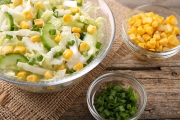Tasty salad with Chinese cabbage, corn and green onion on wooden table, closeup