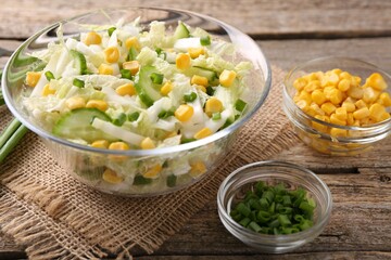 Tasty salad with Chinese cabbage, corn and green onion on wooden table, closeup
