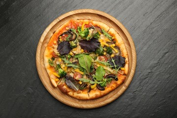 Delicious vegetarian pizza with mushrooms, vegetables and greens on black table, top view