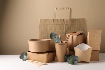 Eco friendly food packaging. Paper containers, tableware, bag and eucalyptus branches on white...