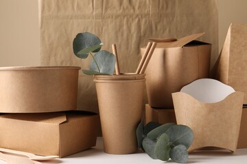 Eco friendly food packaging. Paper containers, bag and eucalyptus branches on white table