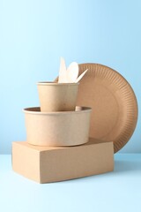 Eco friendly food packaging. Paper containers and tableware on white table against light blue background