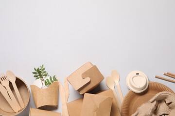 Eco friendly food packaging. Paper containers, tableware and green twigs on light grey background, flat lay. Space for text
