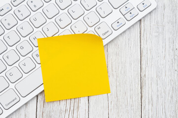 Computer keyboard with a yellow sticky note - 786607543