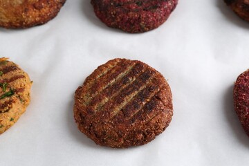 Different tasty vegetarian cutlets on parchment paper, closeup