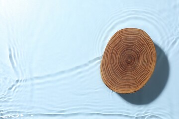 Presentation of product. Wooden podium in water on light blue background, top view. Space for text