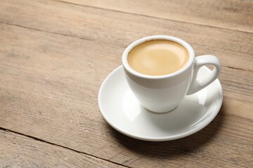 Aromatic coffee in cup on wooden table. Space for text