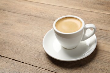 Fototapeta premium Aromatic coffee in cup on wooden table. Space for text