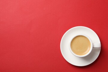 Aromatic coffee in cup on red background, top view. Space for text