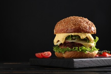 Vegetarian burger with delicious patty on black wooden table. Space for text