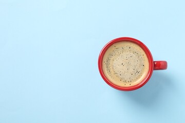 Tasty coffee in cup on light blue background, top view. Space for text