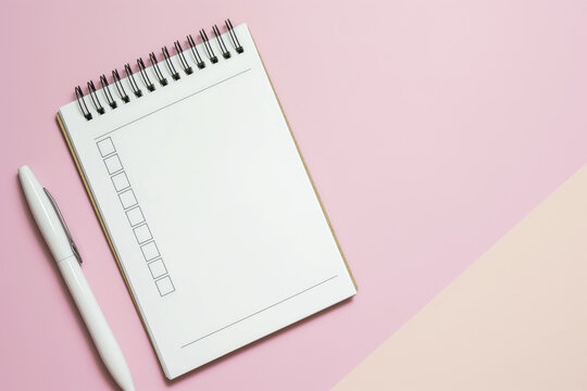 Minimalist to-do list notepad with empty checkboxes beside a white pen on a soft pink surface