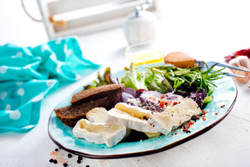Camambert, beet salad and bread on blue plate