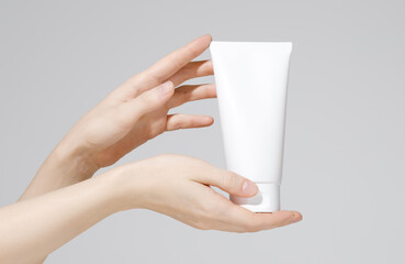 Female hands holding blank white plastic cosmetic tube on white background. Mockup