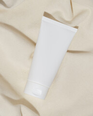 Empty white plastic tube for cosmetics on a towel. Mockup. Packaging for cream, gel, serum