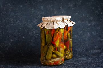 Two glass jars with canned cucumbers and paprika. Natural light