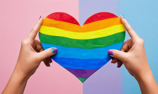 Illustration of hands holding an LGBT rainbow heart, symbolizing love, acceptance,  inclusivity, diversity and unity within the LGBTIQA+ community. Pride month, Pride Day celebration