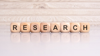 wooden blocks displaying the word 'RESEARCH' arranged on a glossy gray surface