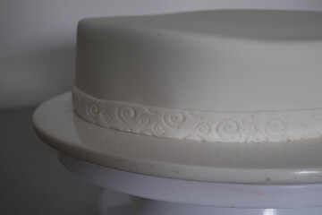 A white cake with a white ribbon on top of a white cake stand emptiness blank fresh start