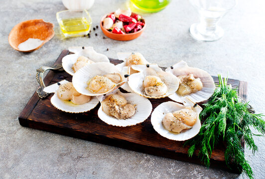 From above fresh appetizing scallop with shell served on wooden boars