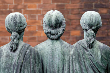 Sculpture en bronze de trois femmes regardant un mur. Cimetière monumental, Milan - Italie