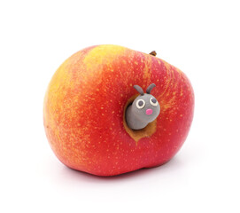 Plasticine caterpillar next to an apple with a hole.
