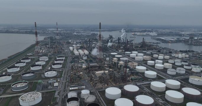 Large petrochemical cracking refinery in the port of Antwerp. Producing fossil fuels. Aerial dorne view at dusk. Large storage containers and industrial installation.