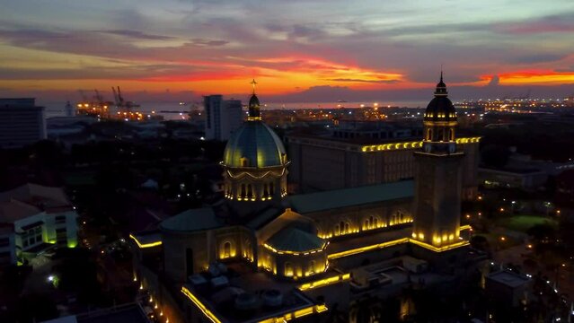 Aerial Panning Scenic View Of Illuminated Cathedral In City Under Cloudy Sky During Sunset - Manila, Philippines