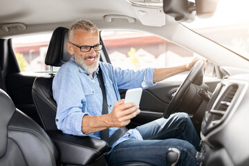Senior man using a smartphone in the car