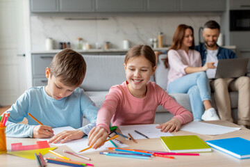 Cheerful siblings engaged in coloring at home