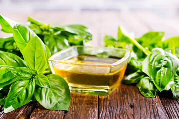Basil oil and fresh herbs on wooden table