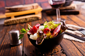 salad with jamon and red wine on wooden table