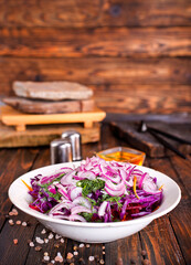 Fresh salad with onion, tomatoes and mixed greens on wooden background top view. Healthy food.