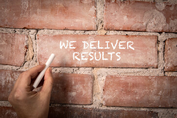 We Deliver Results. Text written with white chalk on a red brick background - 786635916
