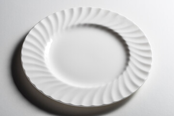 Empty white dinner plate with wavy relief edge