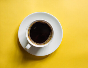 A cup of black coffee on a yellow background.