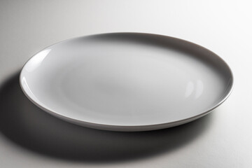 Empty white dinner plate without wing with slightly curved edge with a modern design