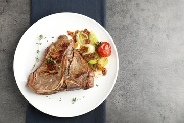 Delicious fried beef meat and vegetables on grey table, top view. Space for text