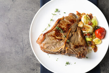 Delicious fried beef meat and vegetables on grey table, top view