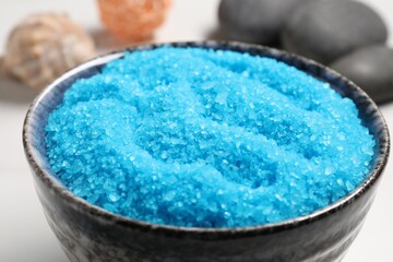 Light blue sea salt in bowl on white table, closeup