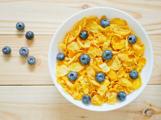 Golden cornflakes cereal with blueberries on wooden background