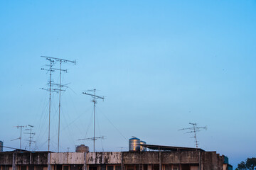Old style Television (TV) Antenna and satellite on the roof with the house or building in provincial area in blue sky with cloud Background in Thailand,Analog TV receiver panels