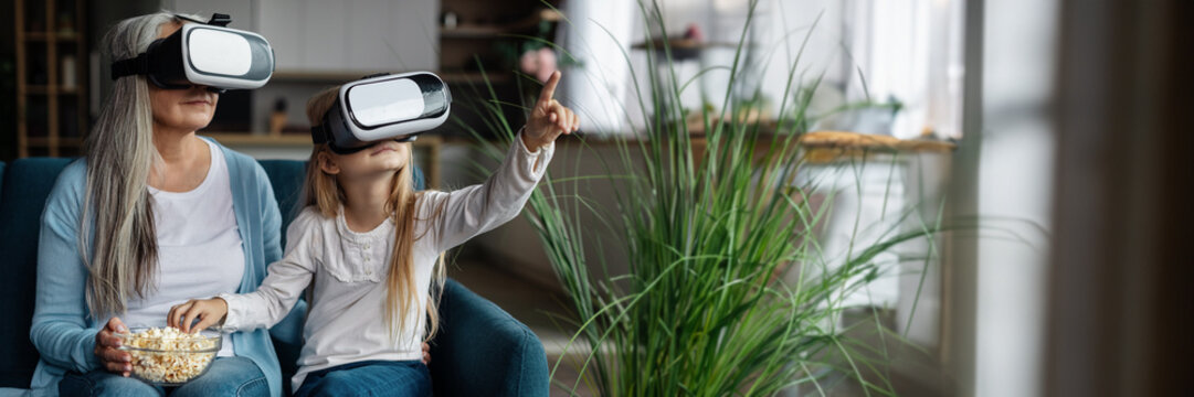 Cheerful european little granddaughter and old grandmother in vr glasses - Powered by Adobe