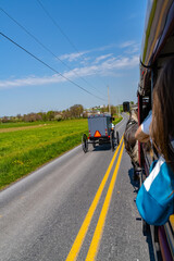 A view from a tour wagon captures an Amish buggy traveling down a rural road in Lancaster, PA,...